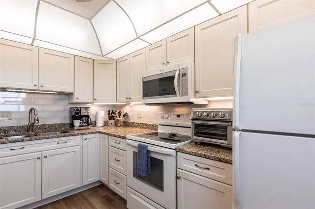 a kitchen with stainless steel appliances granite countertop a sink a stove a microwave and cabinets