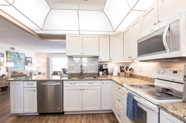 a kitchen with stainless steel appliances granite countertop a sink a stove a microwave and wooden cabinets