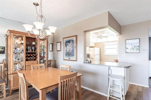 a dining room with wooden floor a chandelier a wooden table and chairs