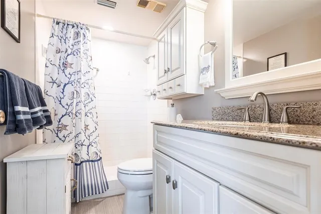 a bathroom with a granite countertop sink a toilet and a mirror
