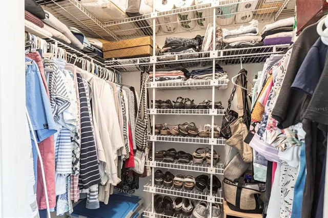 a view of walk in closet with clothes and shoes