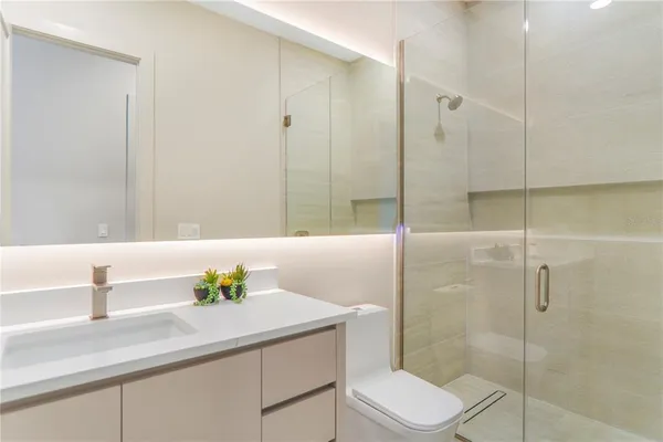 a view of a hallway with wooden floor and a bathroom