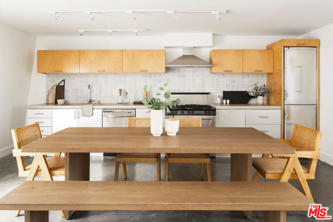 615 Hampton Drive, Unit A101 Venice, CA 90291 - Photo 7 of 24 a kitchen with stainless steel appliances granite countertop a table chairs in it and wooden floors