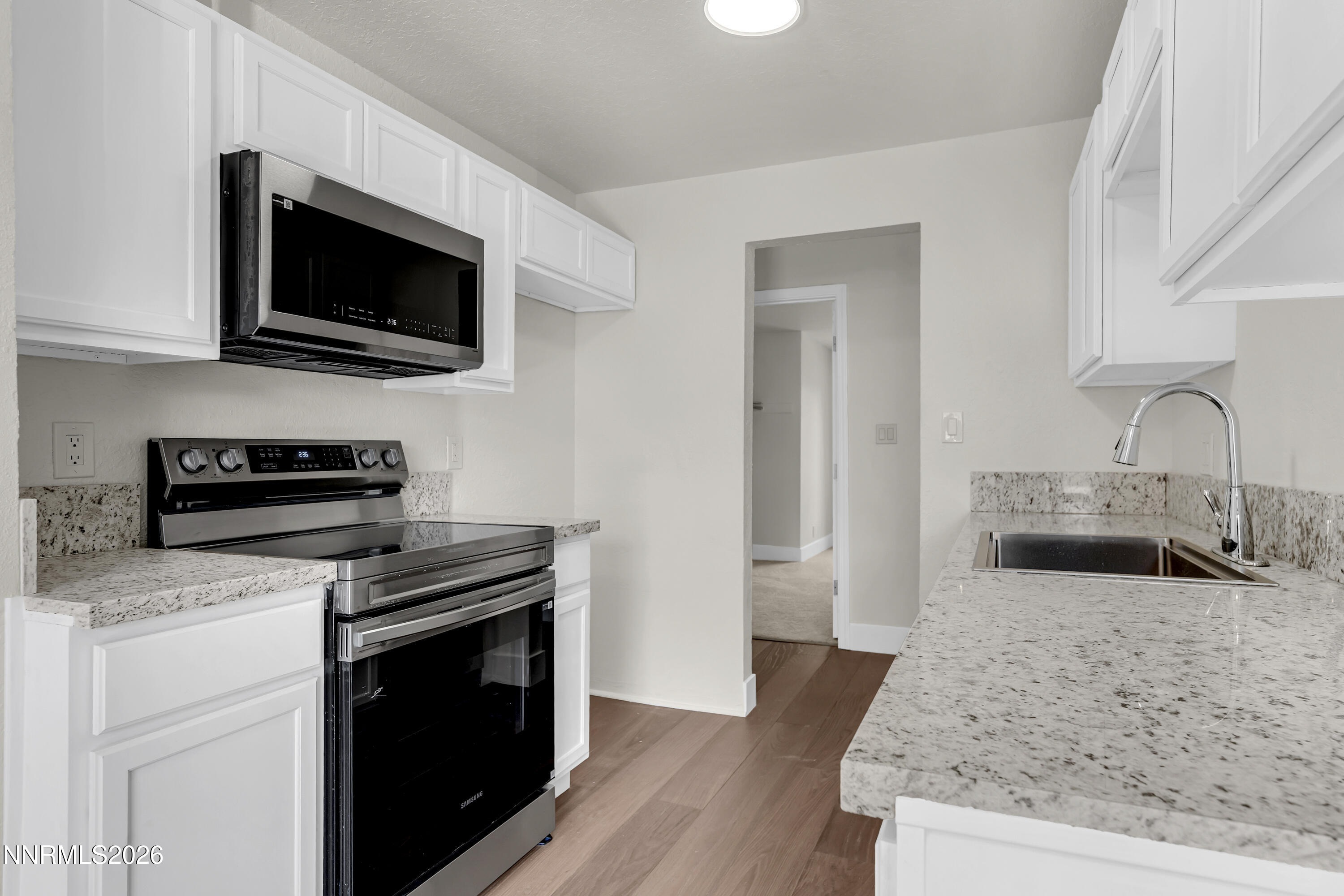 3905 Clear Acre Lane, Unit 26 Reno, NV 89512 - Photo 3 of 27 a kitchen with stainless steel appliances kitchen island granite countertop a stove and a microwave