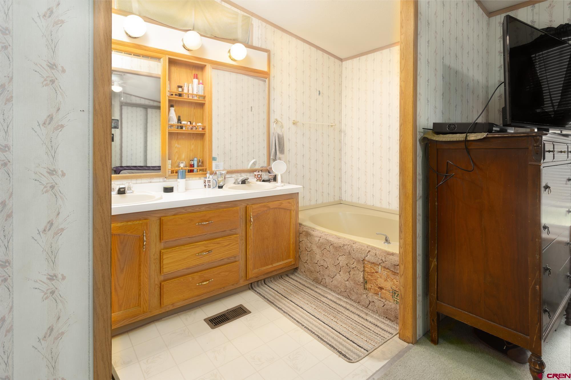 875 Browning Avenue Ignacio, CO 81137 - Photo 17 of 24 a bathroom with a double vanity sink a mirror and a bathtub