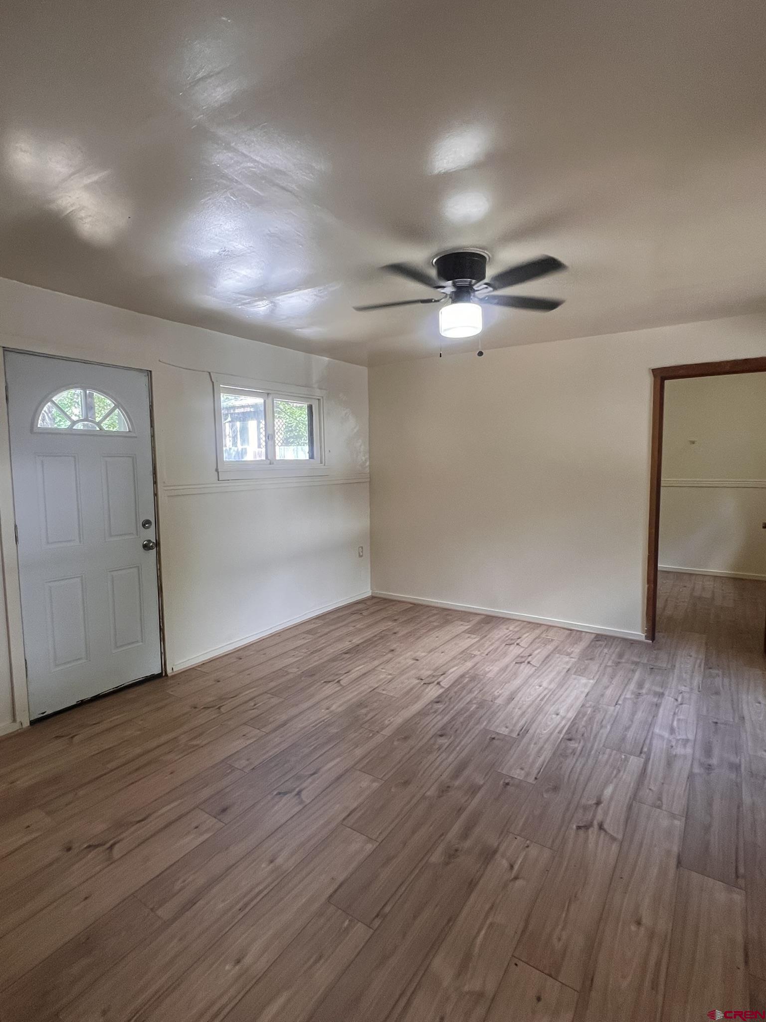 875 Browning Avenue Ignacio, CO 81137 - Photo 3 of 24 an empty room with wooden floor chandelier fan and windows