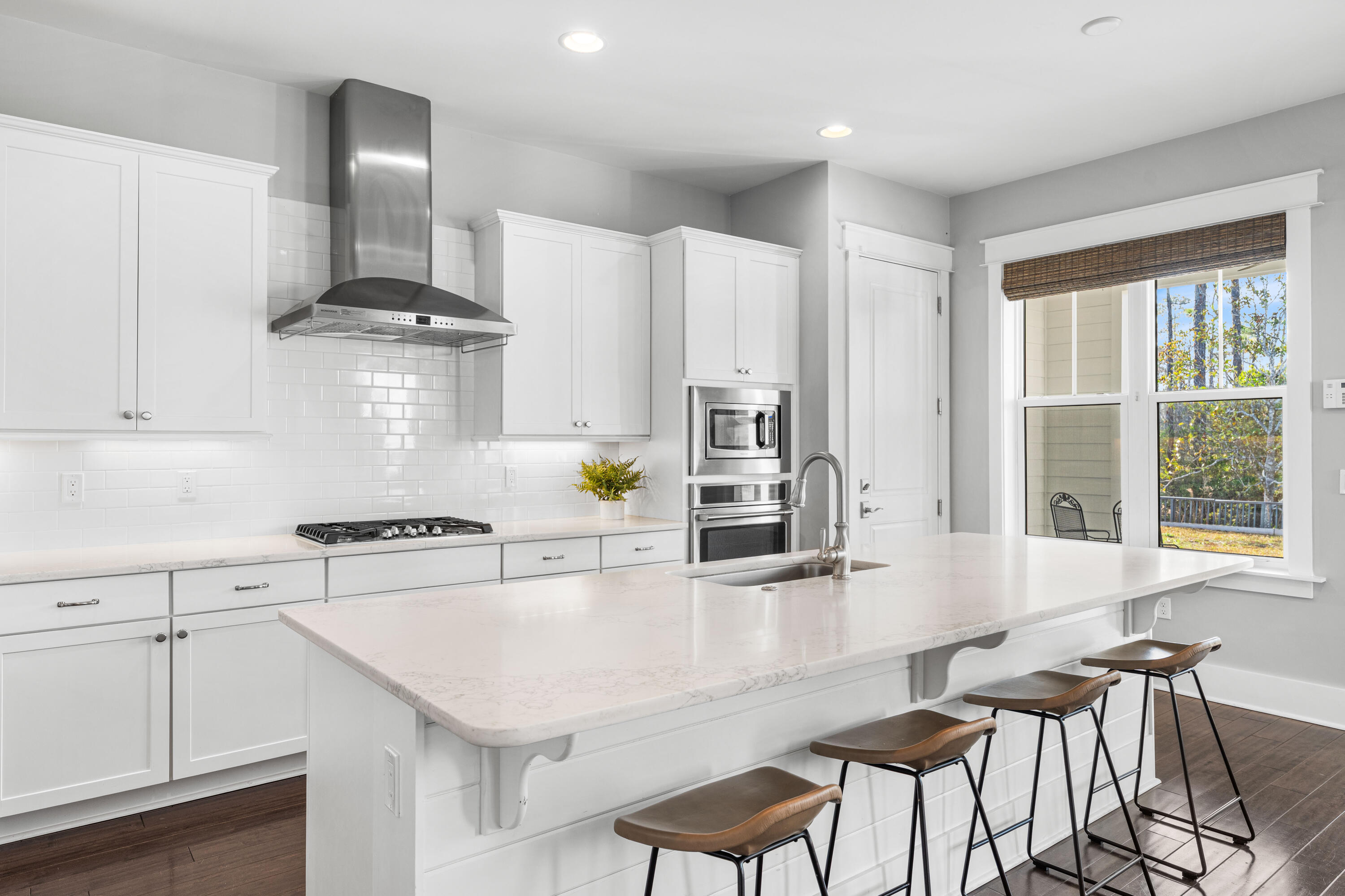 1085 Sandgrass Boulevard Santa Rosa Beach, FL 32459 - Photo 17 of 62 a kitchen with stainless steel appliances kitchen island granite countertop a table chairs in it and wooden floors
