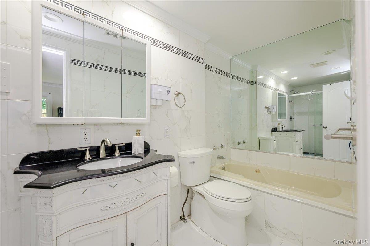 70 Longfellow Road Great Neck, NY 11023 - Photo 19 of 28 a bathroom with a granite countertop sink a toilet a mirror and bathtub