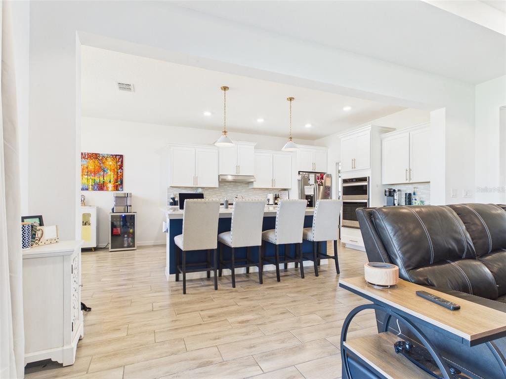 6224 Southwest 74th Ter Road Ocala, FL 34474 - Photo 25 of 52 a living room with couches chairs and kitchen view with wooden floor