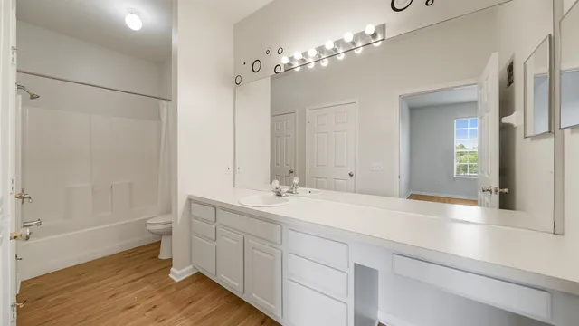 a spacious bathroom with a double vanity sink a large mirror and a shower