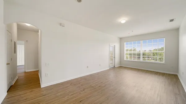 a view of an empty room with wooden floor and a window