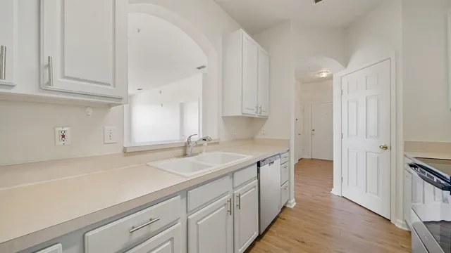 a kitchen with a sink dishwasher and cabinets with wooden floor