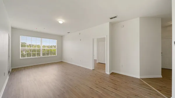 a view of an empty room with wooden floor and a window