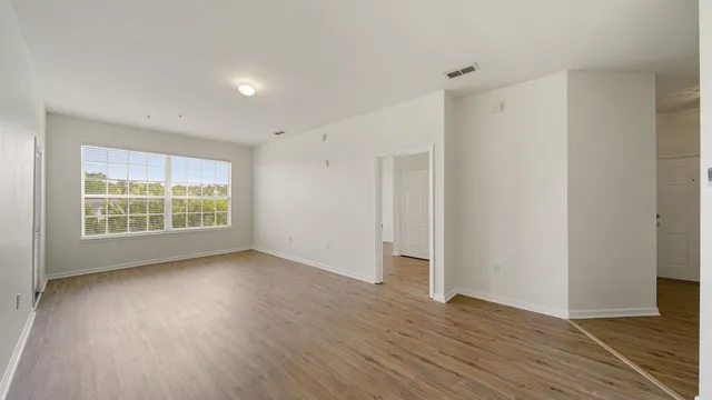 a view of an empty room with wooden floor and a window