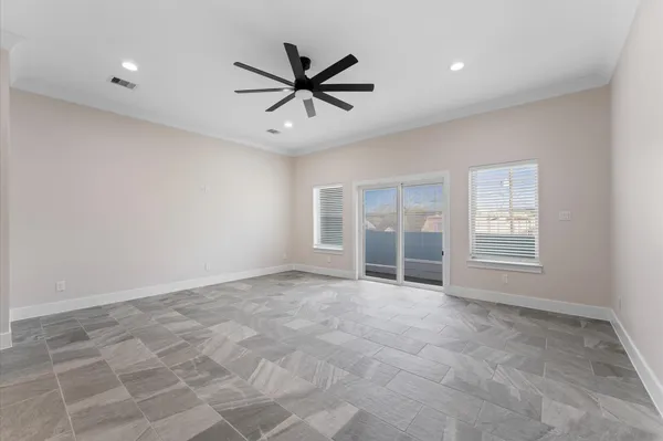 an empty room with ceiling fan and windows