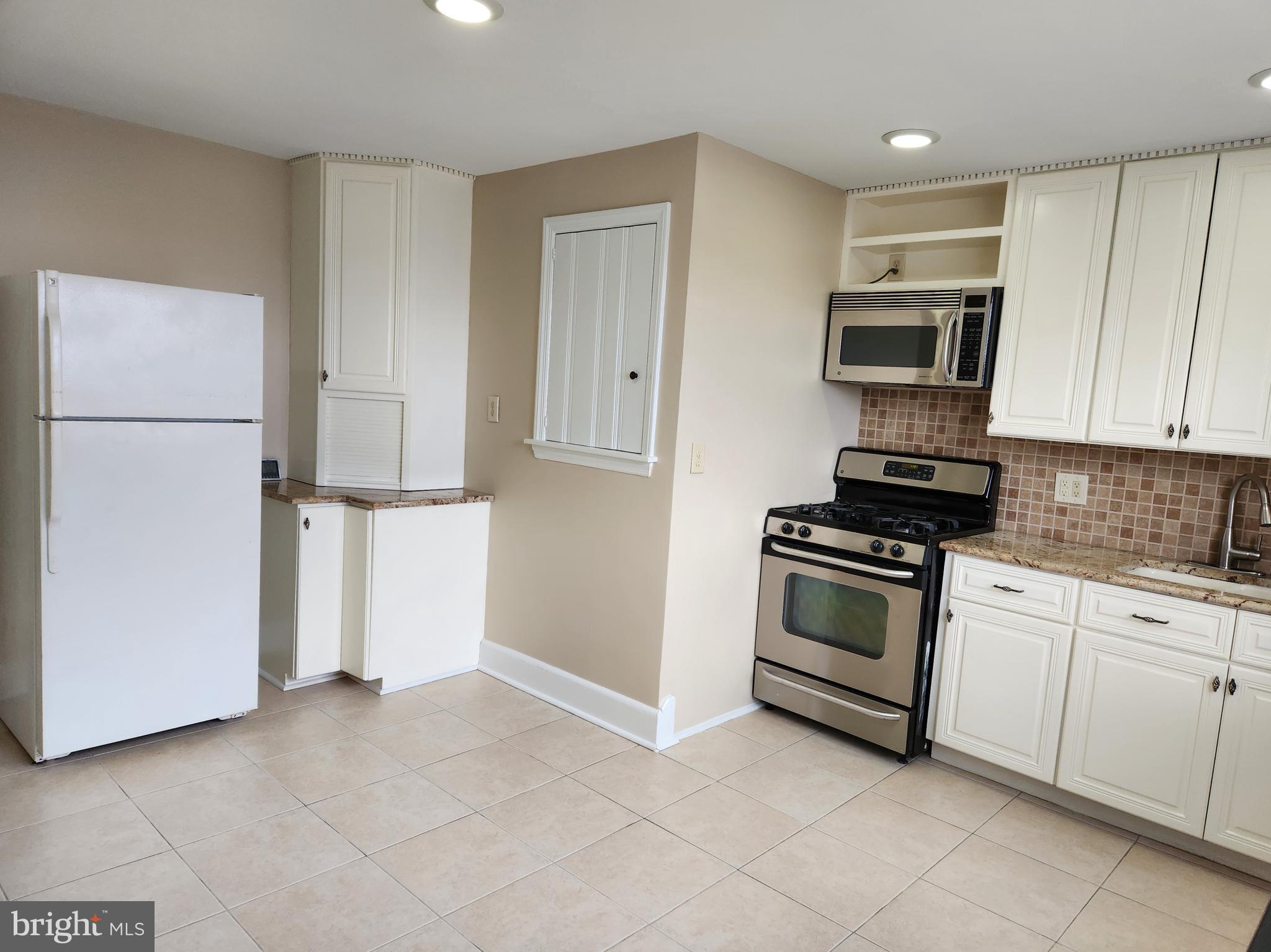 a kitchen with granite countertop a refrigerator and a stove top oven