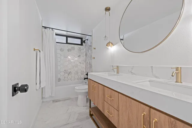 a spacious bathroom with a granite countertop sink a toilet a mirror and shower