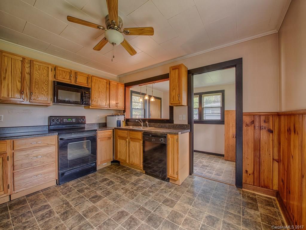 277 Chelsea Road Waynesville, NC 28786 - Photo 12 of 18 a kitchen with granite countertop a stove top oven a sink dishwasher a dining table and chairs with wooden floor