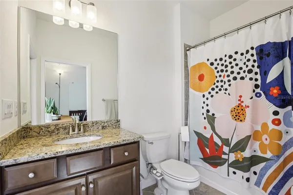 a bathroom with a granite countertop sink and a mirror with toilet