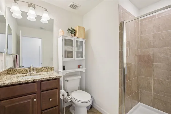 a bathroom with a granite countertop sink a toilet and a mirror