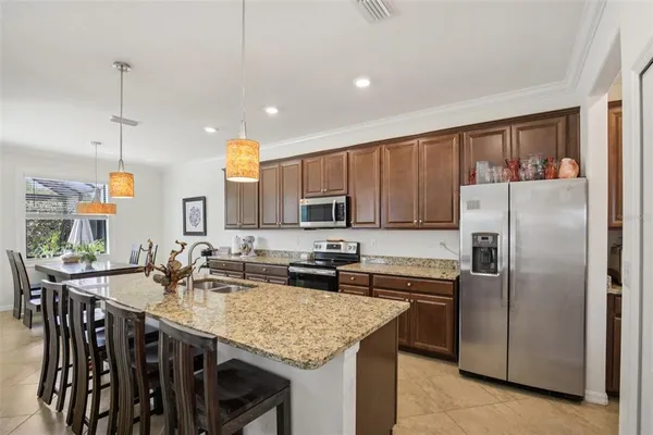 a kitchen with stainless steel appliances granite countertop a kitchen island a stove a table and chairs