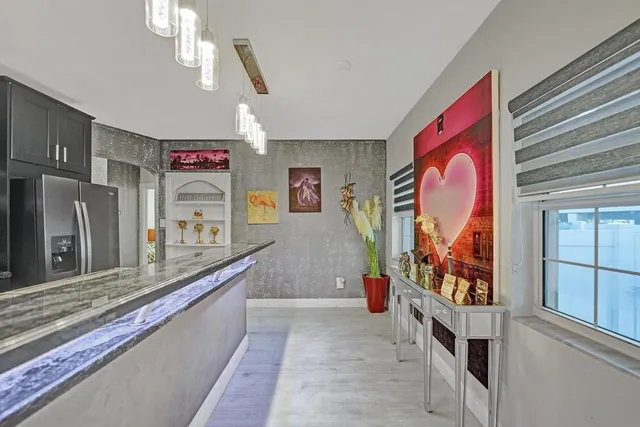 a kitchen with kitchen island granite countertop a stove a refrigerator a sink dishwasher a dining table and chairs with wooden floor