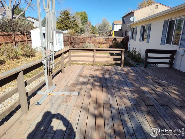a view of a patio with wooden floor and iron fence