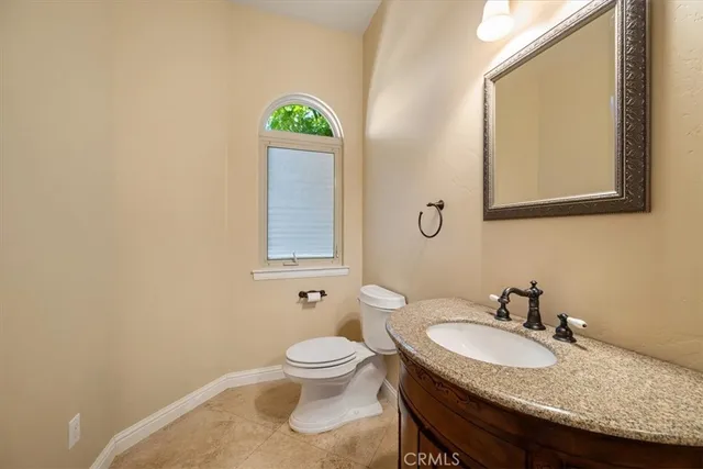 a bathroom with a granite countertop toilet sink and mirror