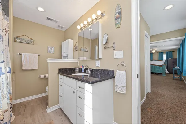 a en suite bathroom with a granite countertop sink a mirror and a shower