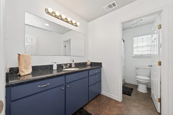 a bathroom with a granite countertop sink a toilet and a mirror