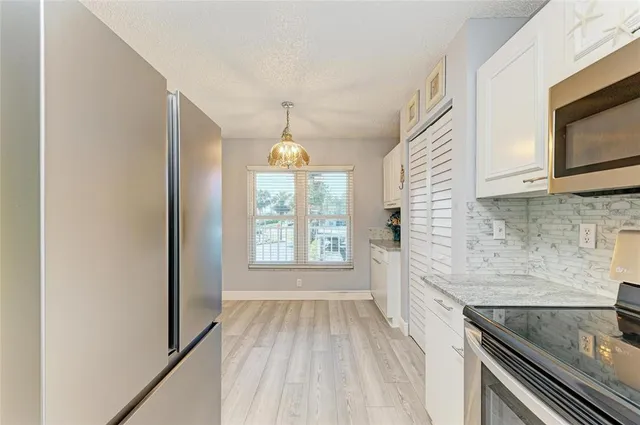 a kitchen with granite countertop white cabinets and appliances