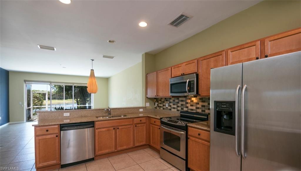 a kitchen with stainless steel appliances granite countertop a refrigerator and a stove top oven