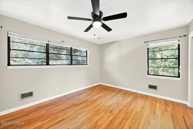 a view of empty room with wooden floor and fan
