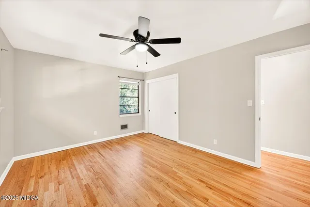 a view of empty room with wooden floor and fan