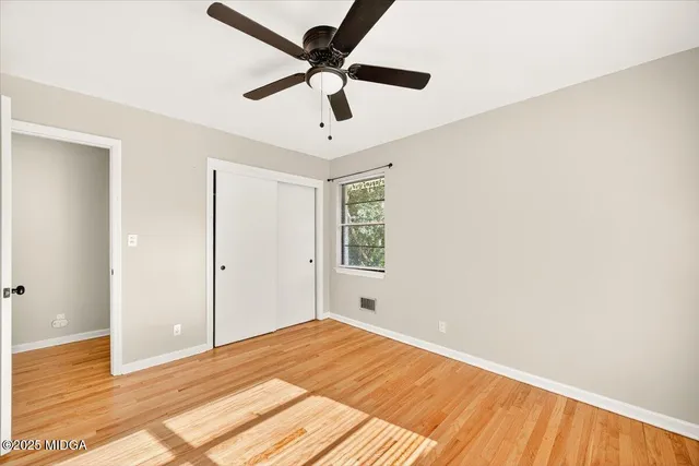a view of a big room with wooden floor and a ceiling fan