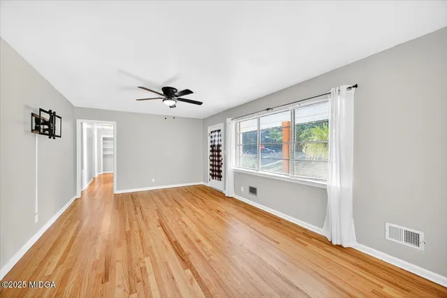 a view of an empty room with a window and wooden floor