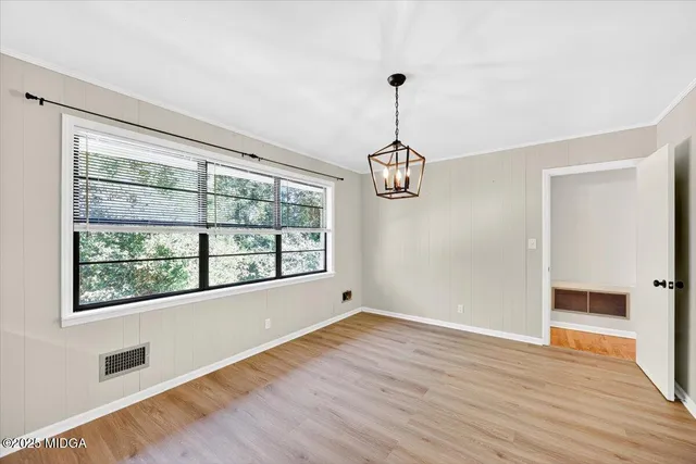 a view of empty room with wooden floor and window