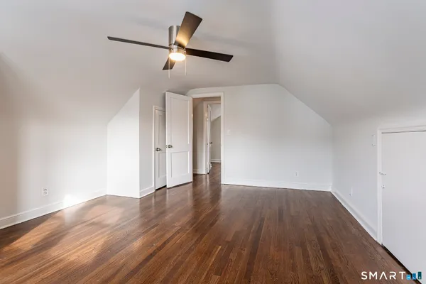an empty room with wooden floor ceiling fan and window