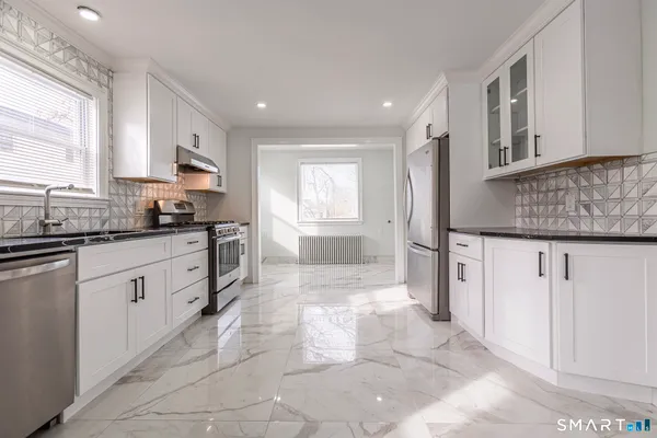 a large kitchen with stainless steel appliances kitchen island granite countertop a sink and cabinets