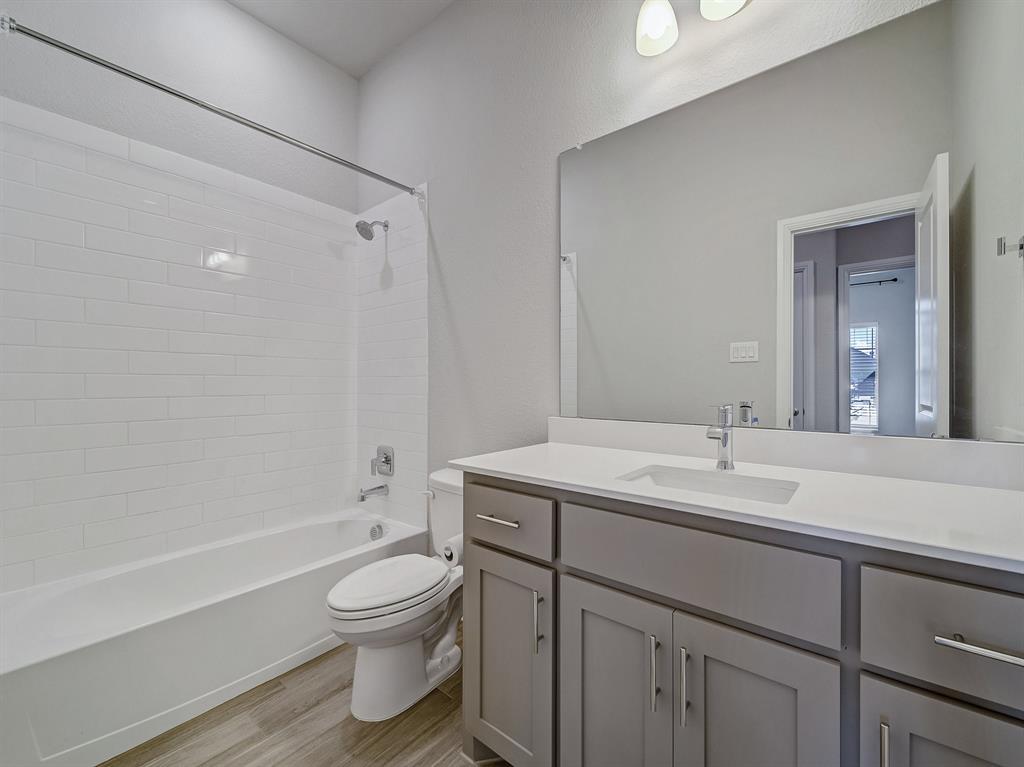 3443 April Breeze Trail Grand Prairie, TX 76065 - Photo 20 of 29 a bathroom with a granite countertop sink toilet a large mirror a bathtub and shower