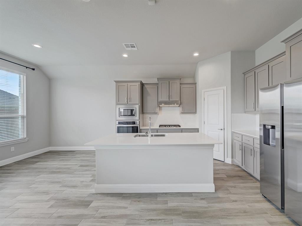 3443 April Breeze Trail Grand Prairie, TX 76065 - Photo 6 of 29 a kitchen with kitchen island stainless steel appliances a refrigerator and a stove top oven