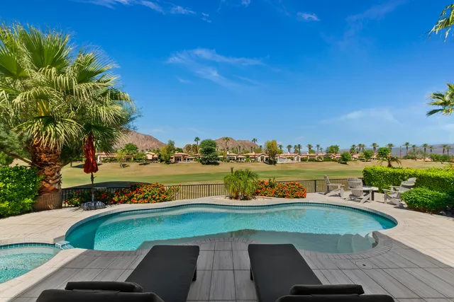 a view of a swimming pool with lawn chairs and a yard