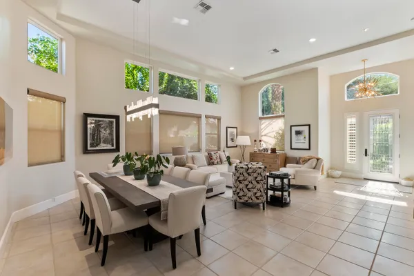 a living room with furniture and three large windows