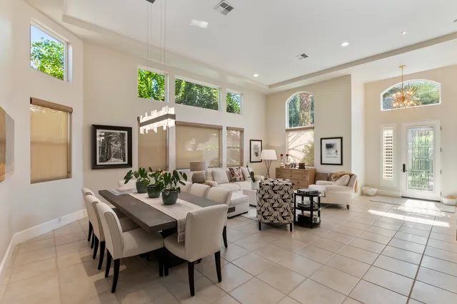 a living room with furniture and three large windows