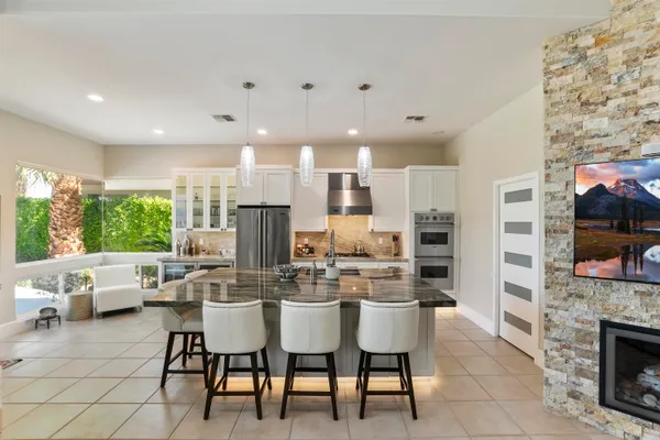 a kitchen with stainless steel appliances kitchen island granite countertop a dining table chairs stove a refrigerator and cabinets