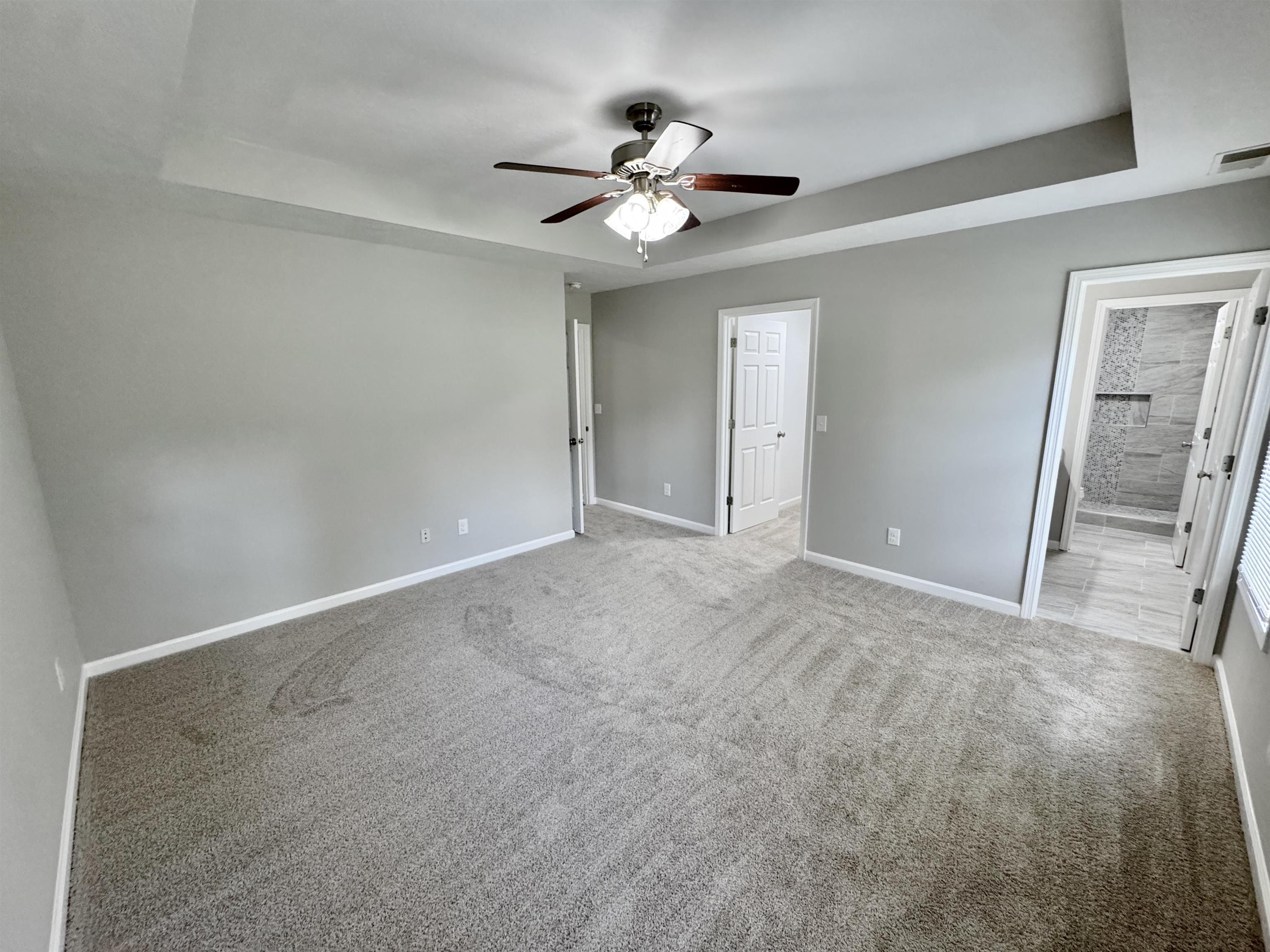 526 Stone Ridge Pinson, TN 38366 - Photo 26 of 39 Unfurnished bedroom featuring a tray ceiling, carpet flooring, a ceiling fan, and ensuite bath