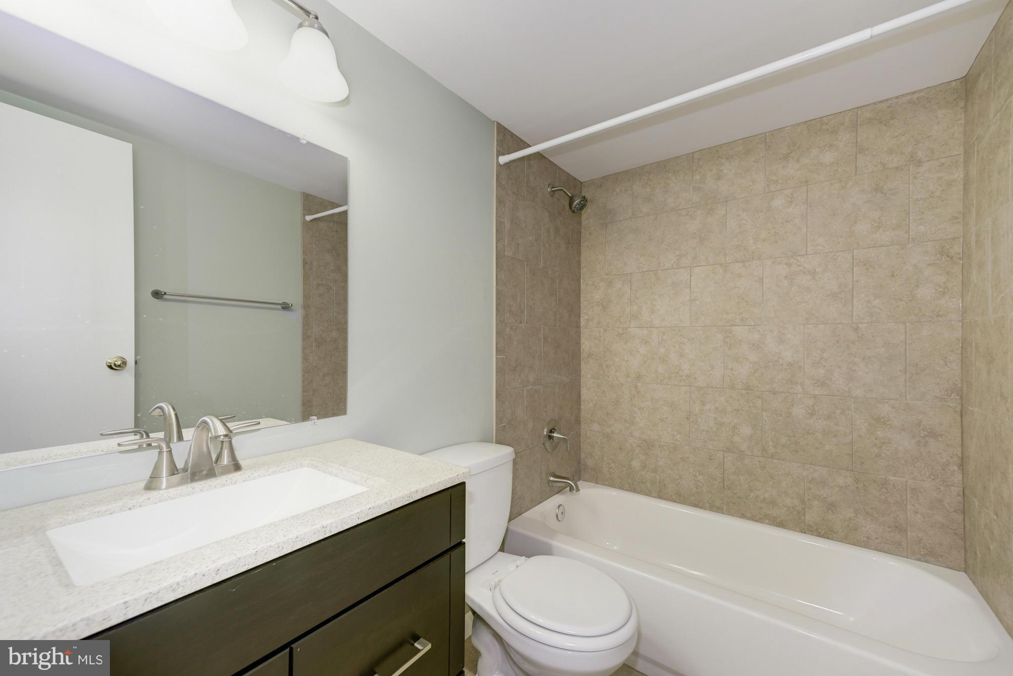 11727 Ledura Court, Unit T2 Reston, VA 20191 - Photo 16 of 18 a bathroom with a granite countertop bathtub shower sink vanity mirror and toilet