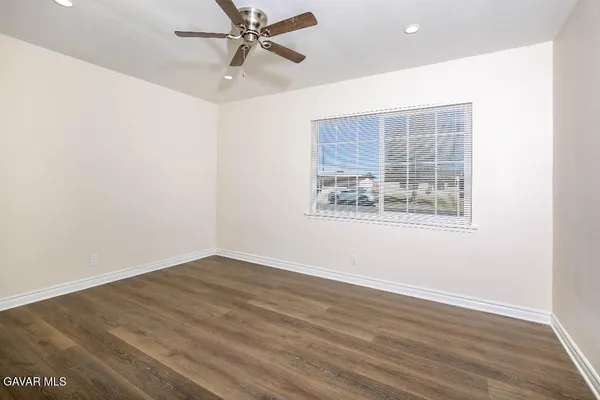 an empty room with wooden floor fan and windows