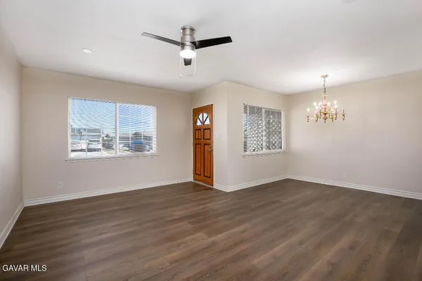 an empty room with wooden floor chandelier and windows