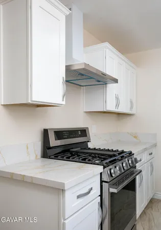 a kitchen with stainless steel appliances granite countertop white cabinets and a stove top oven